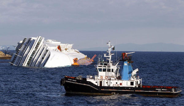 A boat with rescue workers (R) is seen near the Costa Concordia cruise ship that ran aground off the west coast of Italy, at Giglio island Jan 17, 2012. [Photo/Agencies]